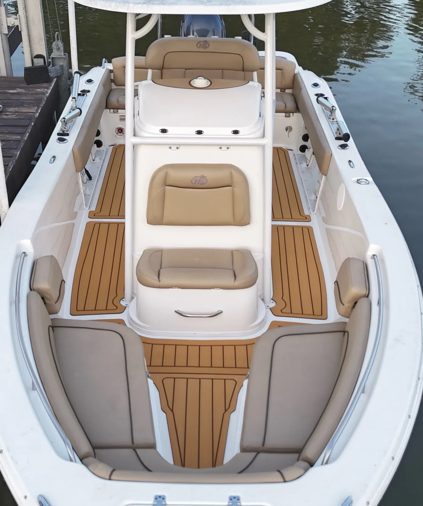 A 2021 Nautic Star 2302 Legacy with tan teak pattern flooring in the bow and cockpit, seen from behind the console